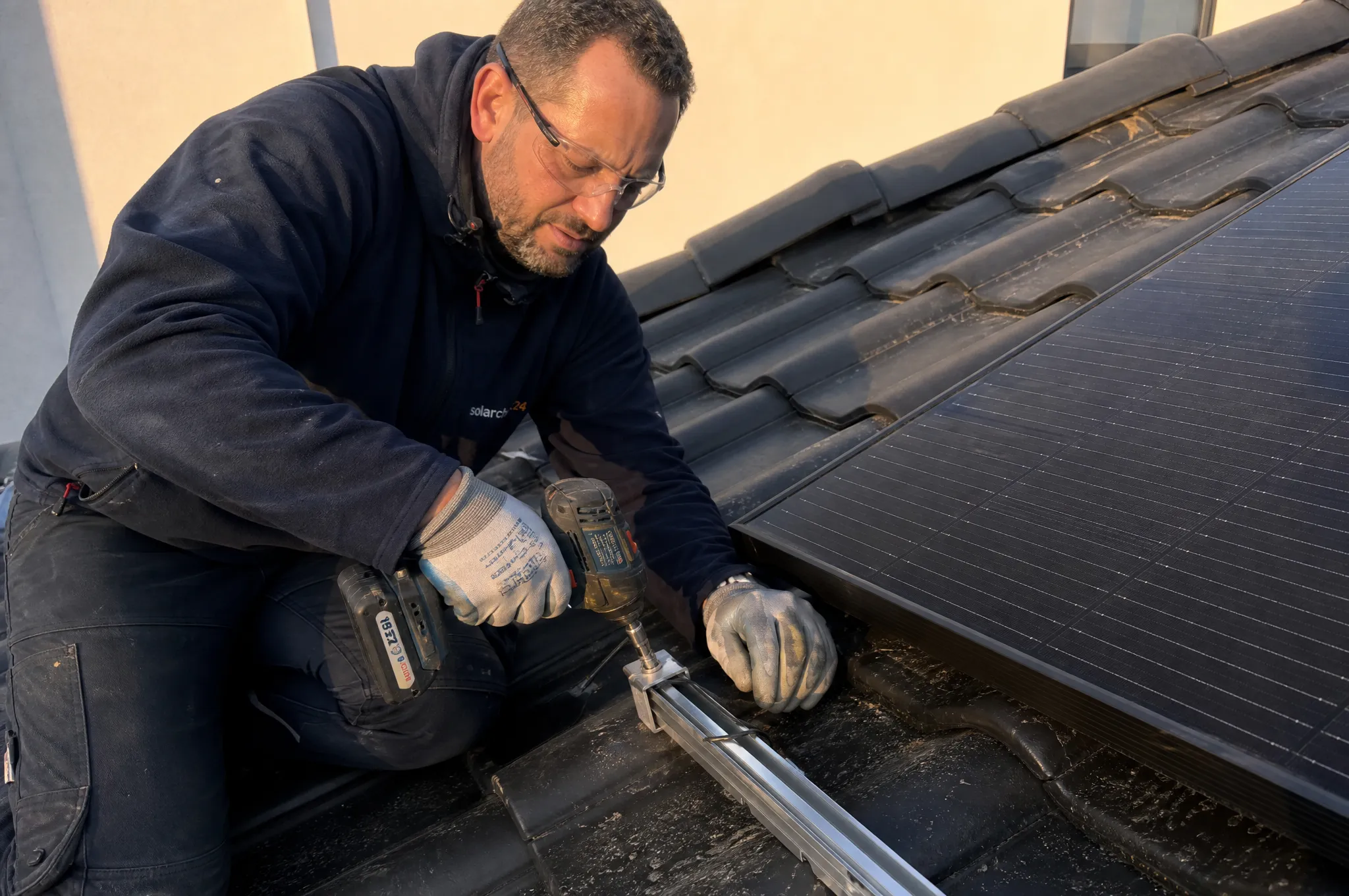 Solarcheck24-Monteur befestigt ein Solarmodul auf dem Dach